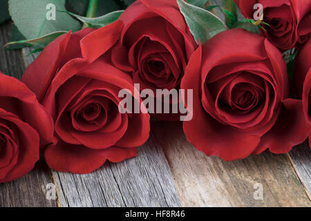 Nahaufnahme von roten Rosen auf Holztisch. Stockfoto