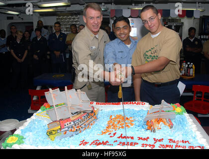 Lt. CMdR Matt Wells (links), Petty Officer 1st Class Emmanuel Torquido und Seaman Denis Lipatnikov machen den ersten Schnitt in einen Kuchen während einer Zeremonie zum Gedenken an die Schlacht Flamborough Head auf den Chaos-Decks an Bord der amphibischen Angriff Schiff USS Bonhomme Richard. Die Zeremonie fand in Erinnerung an den schicksalhaften Kampf zwischen das britische Schiff HMS Serapis und Bonhomme Richard im Jahre 1779. Feiern mit Kuchen 118306 Stockfoto