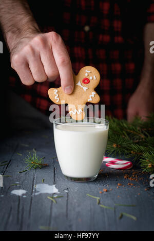 Lebkuchen und Milch. Mann, Lebkuchenmann, Cookie und gehen zu versenken in Glas Milch. Weihnachten Essen Kunst Stockfoto