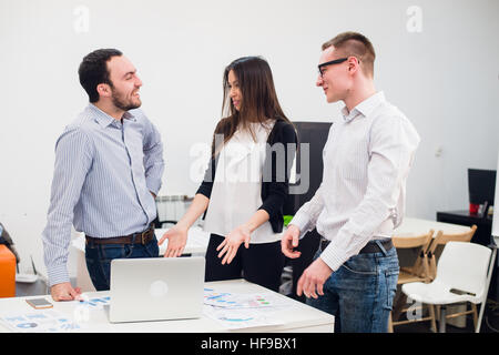 Zusammenarbeit ist der Schlüssel zum Erfolg. Drei junge Geschäftsleute diskutieren etwas beim Betrachten der Computer-Monitor zusammen. Stockfoto