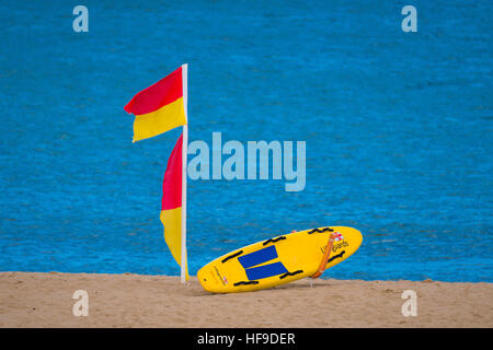 RNLI Rettungsschwimmer Surfbrett und Flaggen am Strand. Stockfoto