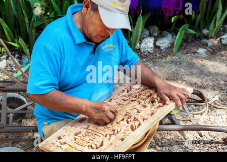 Mann Hand Schnitzen einer traditionellen Maya-Szenenverlaufs aus Holz zu verkaufen an seinem Stand auf dem Gelände von Chichén Itzá Tempel Yucatan, Mexiko Stockfoto