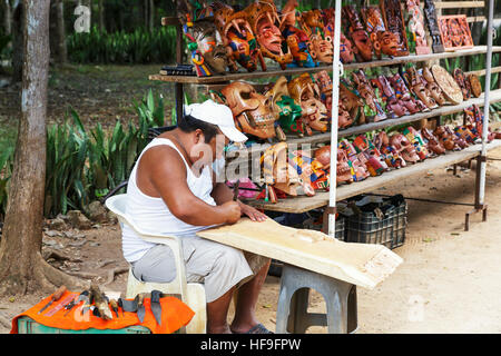 Mann Hand Schnitzen einer traditionellen Maya-Szenenverlaufs aus Holz zu verkaufen an seinem Stand auf dem Gelände von Chichén Itzá Tempel Yucatan, Mexiko Stockfoto