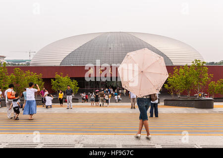 Mädchen hält einen rosa Schirm vor dem nationalen Zentrum für darstellende Kunst aka The Giant Egg, Peking, China Stockfoto