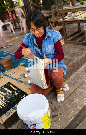 Lao Frau Hand Malerei komplizierten Design auf hausgemachte Keramik Vase. Stockfoto