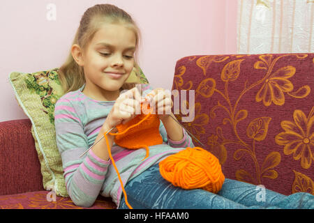 Mädchen auf der Couch liegen und strickt auf Speichen Stockfoto