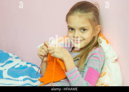 Das Mädchen auf den Nadeln strickt, und sah in den Rahmen Stockfoto