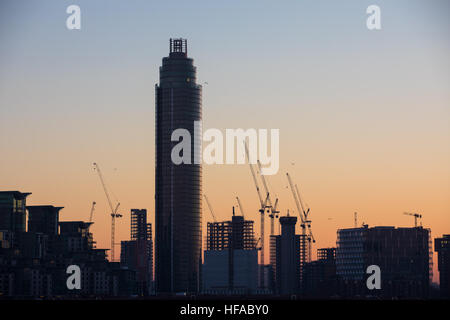 Baukräne Silhouette auf die Skyline von London als die Sonne untergeht. Stockfoto