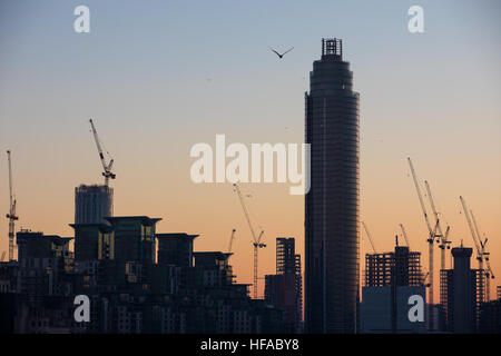 Baukräne Silhouette auf die Skyline von London als die Sonne untergeht. Stockfoto