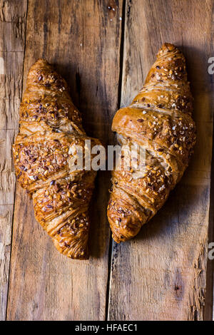 Vollkorn-Croissants auf einem rustikalen distressed Plank Holz Tisch, flache Ansicht von oben, Nahaufnahme, Vintage, gemütliche Atmosphäre Stockfoto