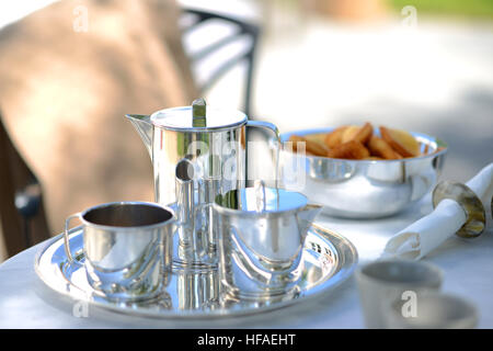 Luxus Silberne Kaffeekanne auf einen Leinen gedeckten Tisch draußen im Sommer. Stockfoto