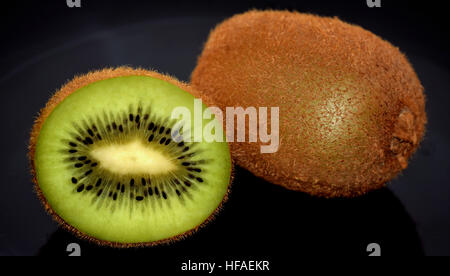 Ein und eine halbe Kiwi auf der schwarzen Platte Stockfoto