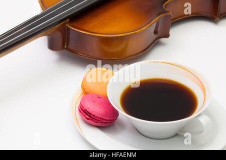 Musik-Pause - alte Geige, Tasse Kaffee und traditionellen französischen bunten Macarons auf dem weißen Tisch Stockfoto