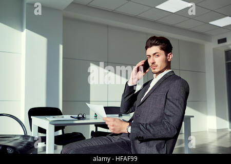 Geschäftsmann am Telefon sitzt einen Stuhl im modernen Büro Stockfoto