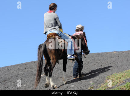 Ein Tourist auf dem Pferderücken wird sich die schwarze Lava Hänge des aktiven Volcan de Pacaya, Cono Mackenney geführt. San Vincente Pacaya. Stockfoto