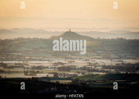 Frostigen Felder und niedrig liegenden Nebel umgeben Glastonbury Tor bei Sonnenaufgang auf der Somerset Ebene nach einer durchzechten Nacht einfrieren Nebel und Minustemperaturen in den südlichen Teilen des Königreichs. Stockfoto