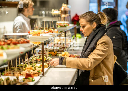 Eine Mädchen erreicht für katalanische Tapas, Pinchos oder Pinchos genannt, in einer Tapasbar in Barcelona. Stockfoto