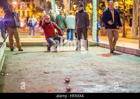 Alte Männer spielen Boule unter den Lichtern des Arc de Triomf in der Nacht in Barcelona. Stockfoto