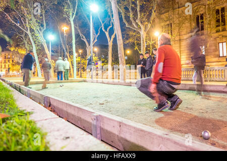 Alte Männer spielen Boule unter den Lichtern des Arc de Triomf in der Nacht in Barcelona. Stockfoto