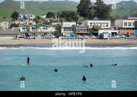 Surfer und Stand Up Paddle Boarder warten auf eine Welle am Strand von Cayucos, Kalifornien, USA Stockfoto