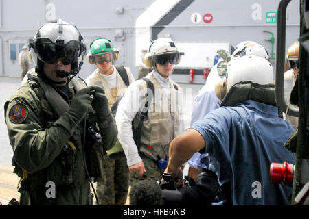 Ein Crewchef zugewiesen Hubschrauber Meer bekämpfen Geschwader 25 schaut zu, wie internationale Medien Personal auf dem Flugdeck der USS Essex (LHD 2) während der Fahrt in der Andamanensee 16. Mai 2008 ein MH-60 s Ritter-Hawk-Helikopter aussteigen. Die Medien besucht Essex und andere Schiffe gemeinsame Task Force Pflege Antwort, gemeinsame humanitäre Hilfe und Katastrophenhilfe Relief, tropischer Zyklon Nargis beteiligt. (US Navy Foto von Lt. CMdR Billy Ray Davis Jr./freigegeben) Defense.gov-Foto-Essay 080516-N-2573D-043 Stockfoto