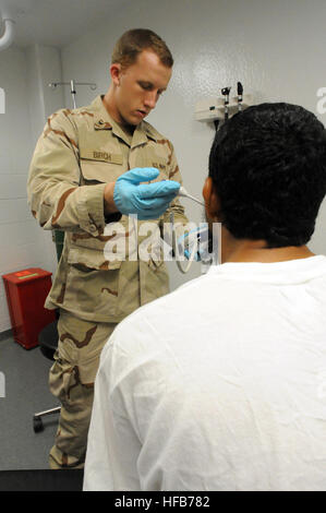 GUANTANAMO BAY auf Kuba – Navy Hospital Corpsman 3. Klasse Nicholas Fouch, mit Joint Task Force Guantanamo Joint Medical Group, nimmt einen Häftling Vitalparameter, 9. Juli 2010. Die JMG stellt die medizinische Versorgung der Gefangenen in Guantanamo JTF. JTF Guantanamo bietet sichere, humane, legale, transparente Pflege und Obhut der Gefangenen, einschließlich der Militärkommission und die verurteilten freigegeben von einem Gericht angeordnete. Die JTF führt Intelligenzansammlung, Analyse und Verbreitung für den Schutz von Insassen und Personal arbeitet in JTF Guantanamo Einrichtungen und zur Unterstützung des Krieges auf Stockfoto