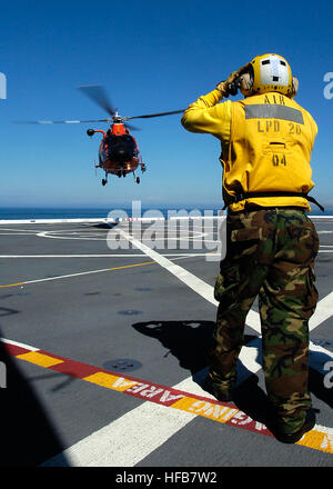 Landung Signal meldete Petty Officer 3rd Class Troy Palomino leitet eine H-65 "Dolphin" kurzfristige Erholung Hubschrauber zugewiesene Gruppe/Air Station Port Angeles, Washington, auf dem Flugdeck der amphibious Transport dock Schiff USS Green Bay. Green Bay unterstützt die Küstenwache mit Übungen im westlichen Pazifischen Ozean. Delfin in Port Angeles 309408 Stockfoto