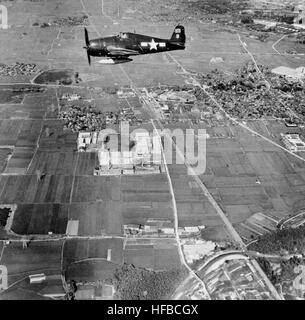 Grumman F6F-5N Hellcat Kämpfer über die Landschaft in der Nähe von Kakagawa, 12. September 1945, mit kleinen Städten und Industrieanlagen auch sichtbar. Fotografiert von einem Flugzeug der USS Bon Homme Richard (CV-31).  Offizielle US-Navy, Foto, jetzt in den Sammlungen der National Archives. F6F-5N VF (N)-91 über Japan im September 1945 Stockfoto