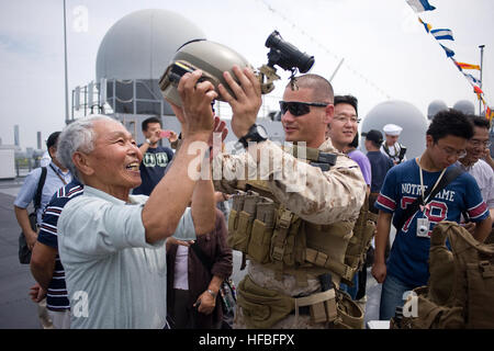 120617-N-CP762-021 Tokio (17. Juni 2012) Staff Sgt Max Veliz, Marine, Flotte Anti-Terrorism Security Team (schnell) Firma Pacific, 3rd Platoon zugewiesen setzt einen Helm auf ein Besucher während einer offenen Schiffstour an Bord der USA 7. Flotte Flaggschiff USS Blue Ridge (LCC-19) in Tokio. Blue Ridge Besuch in Tokio ist ein nach außen Demonstration der US-Engagement für die Verteidigung von Japan, die starke Beziehung zwischen der U.S. Navy und Japan Maritime Self-Defense Force. (Foto: U.S. Navy Mass Communication Specialist 3. Klasse Fidel C. Hart/freigegeben) - offizielle US Navy Bilder - A Marine setzt eine er Stockfoto