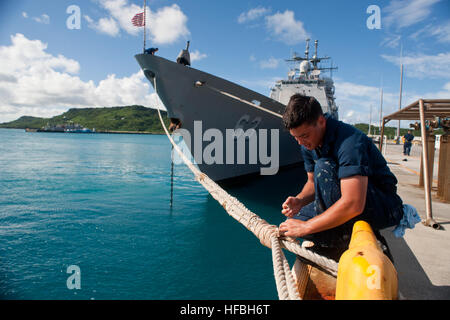 120723-N-TX154-201 OKINAWA, Japan (23. Juli 2012) Seemann Rekrut James McGrath wickelt die Liegeplatz Linien der Ticonderoga-Klasse geführte Flugkörper Kreuzer USS Cowpens (CG-63), kurz nachdem das Schiff Pier-Seite festgemacht. Cowpens ist vorwärts nach Yokosuka, Japan eingesetzt und ist in den USA operierende 7. Flotte Aufgabengebiet. (Foto: U.S. Navy Mass Communication Specialist 3. Klasse Paul Kelly / veröffentlicht) - offizielle US Navy Bilder - A Sailor umschließt eine Befestigungsleine. Stockfoto