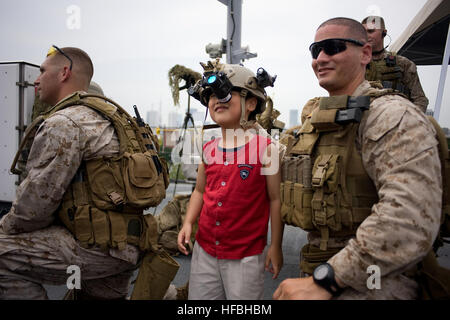 120617-N-CP762-114 Tokio (17. Juni 2012) ein Besucher einen Helm trägt als Staff Sgt Max Veliz, Marine, Flotte Anti-Terrorism Security Team (schnell) Firma Pacific, 3rd Platoon zugewiesen blickt auf in eine offene Schiffstour an Bord den USA 7. Flotte Flaggschiff USS Blue Ridge (LCC-19) in Tokio. Blue Ridge Besuch in Tokio ist ein nach außen Demonstration der US-Engagement für die Verteidigung von Japan, die starke Beziehung zwischen der U.S. Navy und Japan Maritime Self-Defense Force. (Foto: U.S. Navy Mass Communication Specialist 3. Klasse Fidel C. Hart/freigegeben) - offizielle US Navy Bilder - A Besichtigung Stockfoto