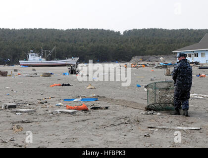 110314-N-MU720-012 MISAWA, Japan (14. März 2011) A Sailor, Naval Air Facility Misawa (NAFM) Hols Schutt während einer Bereinigung Bemühung an der Misawa Fischereihafen zugewiesen. Mehr als 90 Segler aus Naval Air Facility Misawa, Misawa Stadtangestellten und Mitglieder der Community helfen freiwillig beginnen zu bereinigen, nachdem ein Erdbeben und einen Tsunami. (Foto: U.S. Navy Mass Communication Specialist 2. Klasse Devon Dow/freigegeben) - offizielle US Navy Bilder - Segler holt Ablagerungen in Misawa, Japan. Stockfoto