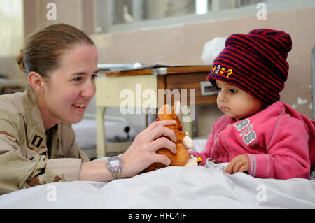 United States Navy Lt. Jessica Gandy gibt eine gefüllte Känguru, ein afghanisches Mädchen in die Indira Ghandi Krankenhaus brennen Kinderstation aufzumuntern, während internationale Service-Mitglieder, die auch International Secuirty Assistance Force Headquarters zugeordnet, andere ausgestopfte Tiere übergehen und Buntstifte für die Brandopfer, Innenstadt von Kabul, Afghanistan, November 20. Das Krankenhaus erhält $400 ist ein Monat, um den gesamten Platz und die Kinderstation brennen führen eine regelmäßige Empfänger der internationalen Hilfe von ISAF Freiwilligen hereingebracht. Lt. Gandy ist Public Affairs Officer für die ISAF. Indira Gandhi Kinder Krankenhaus Burn W Stockfoto