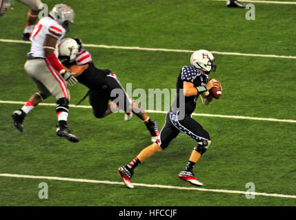 121124-N-WF272-183 AIEA, Hawaii (24. November 2012) ein Spieler, der für die Universität von Hawaii Warriors-Fußball-Nationalmannschaft trägt den Ball während des Spiels Military Appreciation Night im Aloha Stadium, wie seine Teamkollegen die Verteidigung bieten. Die Krieger, die das Spiel mit dem Score von 48-10 gegen die University of Nevada, Las Vegas (UNLV) Rebellen gewonnen trugen maßgeschneiderte roten, weißen und blauen Uniformen und Helme, die nach dem Spiel zugunsten der Wounded Warrior Project versteigert wurden. (US Navy Foto von Massenkommunikation Spezialist Seemann Diana Quinlan/freigegeben) Military Appreciation Night 12112 Stockfoto