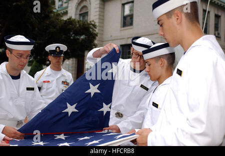 Dadurch von der US Naval Academy-Klasse 2012 Praxis Faltung der nationalen Ensigns als Chief Aviation strukturelle Mechaniker Shawn R. Horigan blickt auf. Plebs Sommer, der sechs-Wochen-Prozess Zivilisten in Midshipmen, verwandeln werden Plebes unterrichtet, die geistigen, moralischen und körperlichen Standards notwendig, effektiv eine All-Volunteer Force von Matrosen und Marinesoldaten führen zu entwickeln. Plebs Sommer am United States Naval Academy 102733 Stockfoto