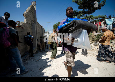 Eine Erdbeben in Haiti Überlebende hinterlässt ein rotes Kreuz Vertriebsstandort nach Empfang Pilzkonserven Artikel in Port-au-Prince, Haiti, 25. Januar 2010. Haiti erlebt ein 7,0 Erdbeben 12. Januar 2010, das Tausende Haitianer obdachlos und ohne Notwendigkeiten wie Seife und decken. Viele Haitianer auf Verteilungspunkte warten auf mehr als vier Stunden, um ein Ticket zu erhalten, die den Inhaber Zugang zu dem Verteilzentrum gewährt. (Foto: U.S. Navy Mass Communication Specialist 1. Klasse Joshua Lee Kelsey/freigegeben) Rotes Kreuz Hilfe Verteilung in Port-au-Prince 2010-01-25-1 Stockfoto