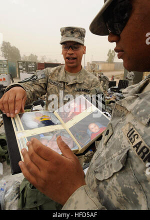 US Army Spc. Marcus Lambert, 33, von Phoenix, Arizona, Alpha-Vertriebsgesellschaft, 215. Brigade Support Battalion, 1. Kavallerie-Division zugewiesen zeigt Spc. Antoine Hunt, 21, Lauringburg, N.C., Fotos von seinem Sohn während sie warten, bis ein Zollinspektor, überprüfen Sie ihre persönlichen Sachen bei einer Zollkontrolle, bei nach vorne Operating Base Marez, im Norden des Irak, 3 November.  Nach Abschluss einer einjährigen Tour im Irak sind Soldaten aus Alpha-Vertriebsgesellschaft für ihre Rückkehr in die Heimat einpacken. Soldaten vorbereiten nach Hause 219900 Kopf Stockfoto