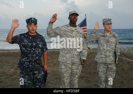 GUANTANAMO BAY auf Kuba – Armee Spc. Carlos Baptista (Mitte), mit der Rhode Island Army National Guard 115. Military Police Battalion, nimmt die Vereinigten Staaten Treueid während seiner Einbürgerung Zeremonie an Bord Naval Station Guantanamo Bay, 19. April 2010. Joint Task Force (JTF) Guantanamo bereitgestellt, geboren Baptista in Kap Verde. Marine Maschinist Mate 3. Klasse Jo Kurosu (links), eine Brigg Wache, Naval Station Guantanamo Bay, zugewiesen und Armee Sgt. Ardicio Galvao (rechts), ein Veterinär-Techniker zugewiesen, die Naval Station Guantanamo Bay Veterinary Clinic, auch den Eid, Bec Stockfoto