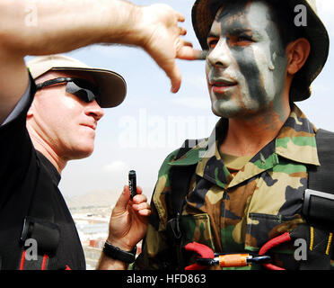 KABUL, Afghanistan (9. August 2010) französische Hauptmann Guillaume Quevarrec, links, EPIDOT Programm Afghan National Army (ANA) Berater, gilt Tarnung Farbe auf das Gesicht des afghanischen Kapitän Abdulhai, vor einer Abseilen Demonstration im Rahmen einer Pre-Ramazan Zeremonie in Kabul Military Training Center (Ausbildungszentrum). ANA und Besuch Koalition Führer sah Sicherheit und schnelle Response-Teams ihre Reaktionen auf simulierte Angriffe Aufständischer zu demonstrieren. Vier ANA Ausbilder im Ausbildungszentrum simuliert einen Gegenangriff durch Brennen Rohlinge aus dem Dach eines mehrstöckigen Gebäudes, dann die Seite Hilfe ich Abseilen Stockfoto