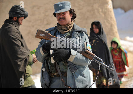 Ein Mitglied der Afghanischen Nationalpolizei bietet Sicherheit, während andere Mitglieder Lebensmittel und kaltem Wetter Kleidung in Molla Owrang Dorf, Nawbahar District, Provinz Zabul, Afghanistan, 7. Februar verteilen.  Die Elemente unterstützen die Dorfbewohner durch den harten Winter.  (Foto: U.S. Navy Mass Communication Specialist 2. Klasse David A. Brandenburg / veröffentlicht) Afghanische Nationalpolizei und Koalition Spezialoperationen Kräfte Essen Handout 120207-N-UD522-181 Stockfoto