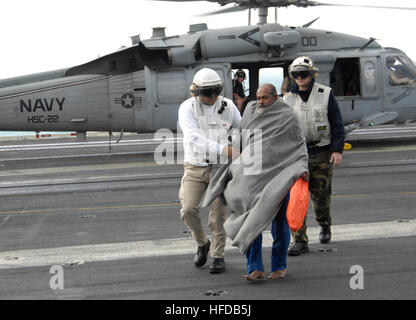 Die letzte der sieben gestrandeten Überlebenden ist auf dem Flugdeck der Flugzeugträger der Nimitz-Klasse USS Harry S. Truman (CVN-75) begleitet, nach seiner Rettung auf See durch zwei Hubschrauber, Hubschrauber Meer Kampf Geschwader 22, die "Meer-Ritter", aus dem schnell Kampfunterstützung Schiff USNS Arctic (T-AOE 8), Dez. 23 zugewiesen. Die sieben Mariners, vier pakistanische und drei indische wurden geborgen, nachdem ihre Dhau in rauer See versank. Die Überlebenden waren für zwei Tage vor der Entdeckung durch das britisch-Flagge fahrenden Schiff MV britische Mut treiben. Truman und der Arktis werden derzeit bis zum arabischen Golf als bereitgestellt. Stockfoto