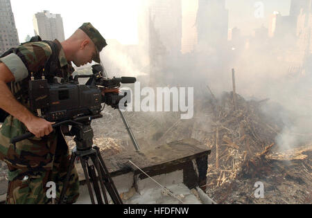 Am 16. September 2001 dokumentiert ein Videofilmer der US Navy den Tatort, an dem das World Trade Center in New York City nach den Terroranschlägen vom 11. September zusammenbrach. Die umliegenden Gebäude wurden durch Schutt und massive Aufprallkräfte stark beschädigt, und die Sanierungsarbeiten sind im Gange. Stockfoto