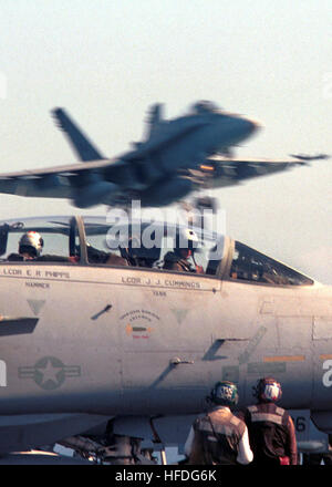 020301-N-3692 H-002 auf hoher See an Bord der USS Theodore Roosevelt (CVN-71) 1. März 2002 - Pilot und sein Radar-Interceptor-Operator (RIO) sitzen in einer f-14 "Tomcat" Kämpfer "Diamondbacks" der Fighter Squadron One Zero Two (VF-102), zugewiesen, während wartet auf Anweisungen von der Cockpit-Crew in Position für den Start bewegen.  Overhead einer F/A-18 "Hornet" strike Fighter Ansätze das Schiff für eine fesselnde Landung, nach der Rückkehr von einer Mission.   Theodore Roosevelt und seine eingeschifften Carrier Air Wing (CVW) führen Kampfeinsätze in Afghanistan zur Unterstützung der Operation Enduring Freedom.  U.S Stockfoto