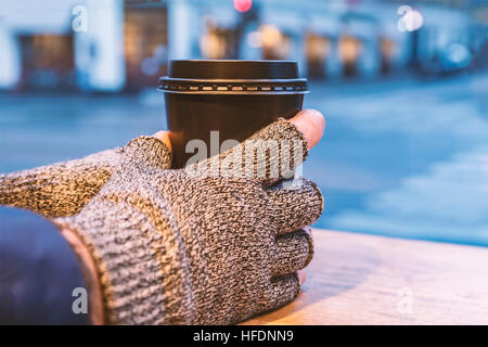 Bild des Mannes Hände mit Handschuhen hält eine Kaffeetasse. Stockfoto