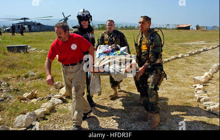 Eine haitianische verwundete kommt an eine medizinische Triage-Bearbeitungszentrum in Port-au-Prince, Haiti, über eine MH-60 s Sea Hawk Hubschrauber während der Operation Unified Response.  Es gibt mehr als ein Dutzend medizinische Zugangspunkte wie in diesem Fall über das Erdbeben lädierten Stadt Port-au-Prince.  Der verletzte Mann wurde von zwei Mitgliedern der Security Force zum Schutz der Website, ein Mitglied der Sea Hawk gebracht? s Flugpersonal und ein Freiwilliger aus medizinischen Schaden Assistance Team (MDAT) Georgien, EMT-Team 3.  Operation Unified Response ist eine internationale Koordination zwischen mehr als 30 Nationen und Hunderte von keine Stockfoto