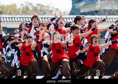 Japan, Kumamoto. Hinokuni Yosakoi Festival. Tänzer, junge Männer und Frauen auf der Bühne im Yukata in roten Hemden, kniend, schreien mit Arm ausgestreckt. Stockfoto