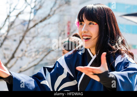Japan, Kumamoto. Hinokuni Yosakoi Festival. Frau Tänzer mit Blume im Haar. Gesicht, lächelnd mit Mund offen, glücklich. Hände und Arme ausgestreckt. Stockfoto