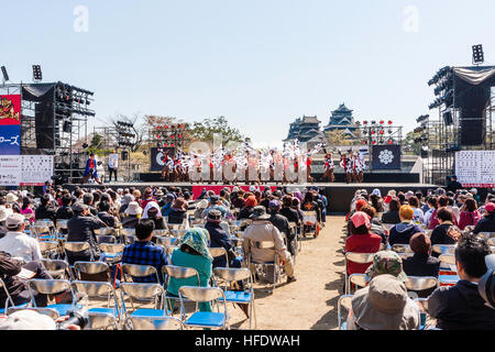 Hinokuni Yosakoi Dance Festival in Kumamoto. Vordergrund, Zuschauer großes Team von Tänzer tanzen auf der Bühne vor dem Schloss. Tagsüber. Stockfoto