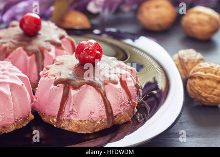 Roh Vegan Dessert mit Sauerkirschen, Datteln und Walnüsse auf schwarzem Teller serviert Stockfoto