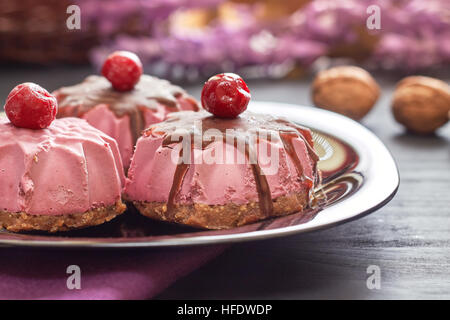 Roh Vegan Dessert mit Sauerkirschen, Datteln und Walnüsse auf schwarzem Teller serviert Stockfoto